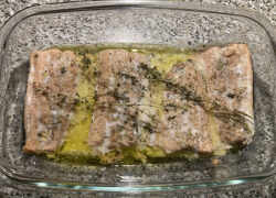 Hotový šťavnatý losos na masle s bylinkami v sklenenej nádobe