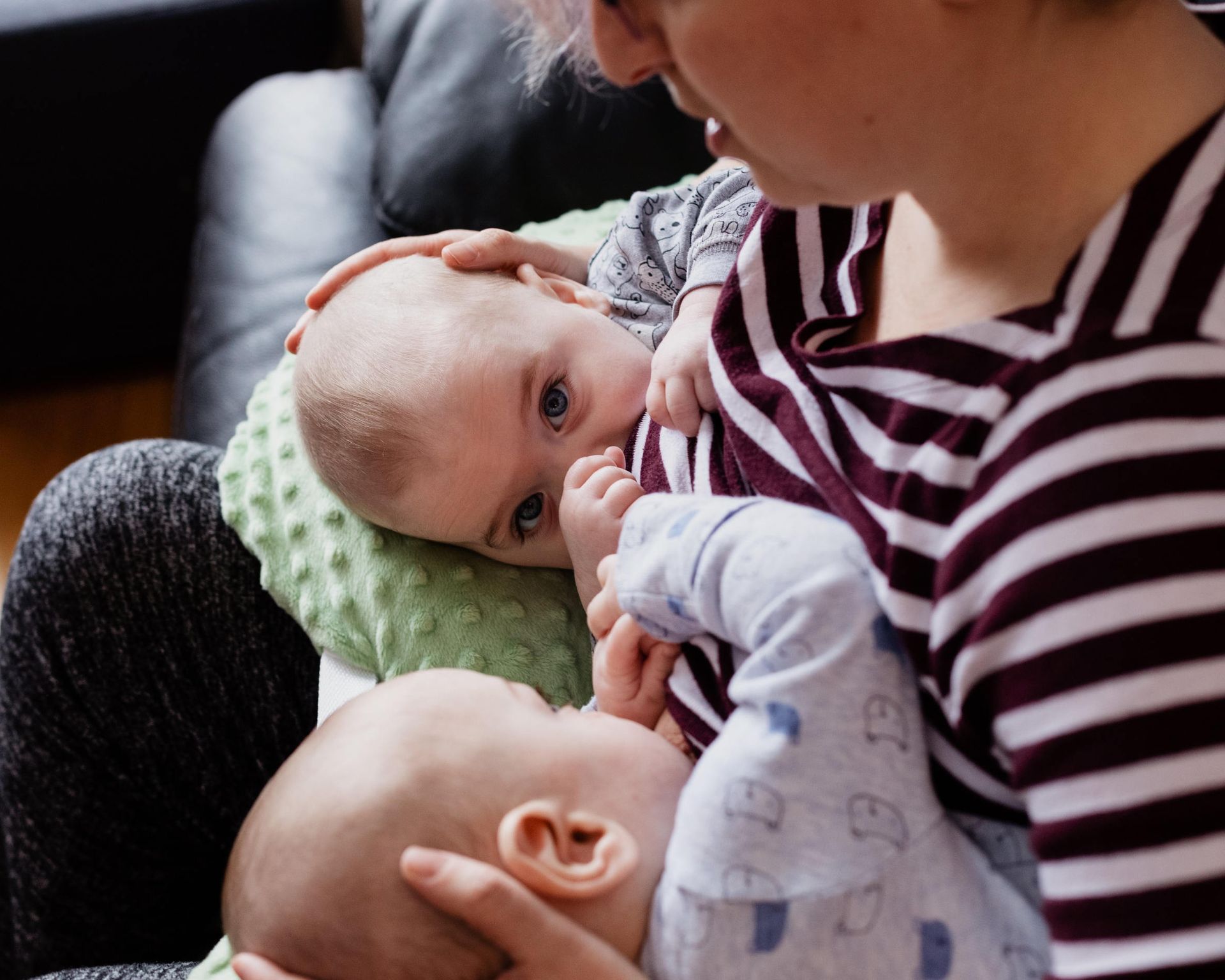 Maminka s dvomi malými bábätkami pri kŕmení na gauči