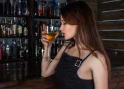 Žena s pohárom nápoja, ktorý obsahuje alkohol