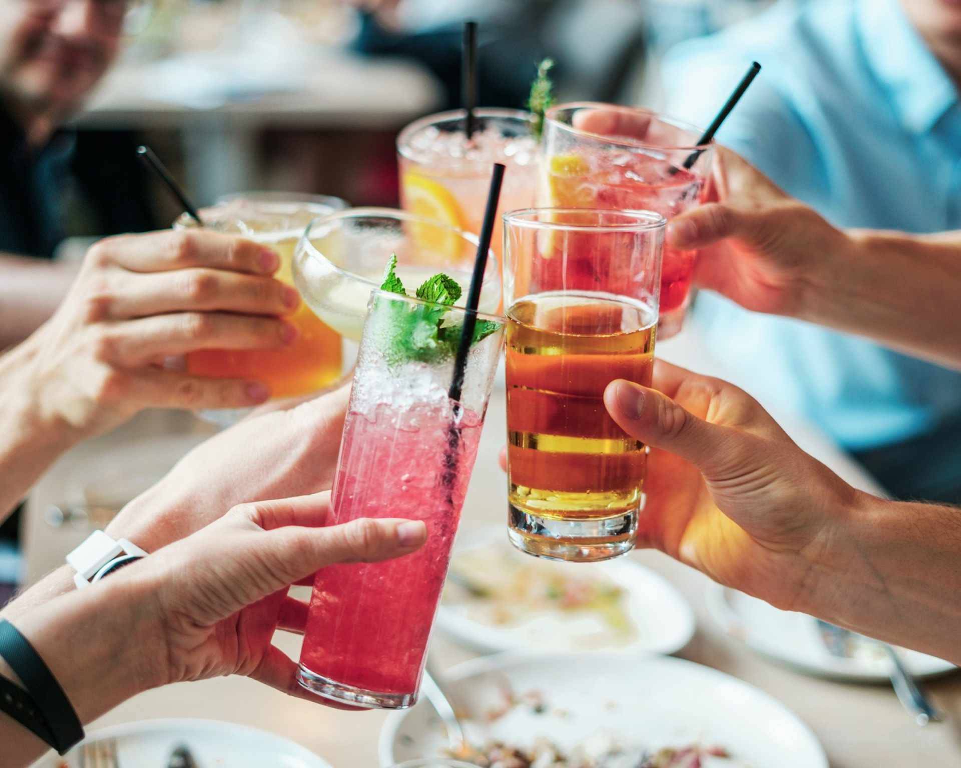 Ľudia držiaci v ruke rôzne alkoholické kokteily