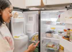 Žena stojí pred otvorenou chladničkou a rozmýšľa čo uvarí - hľadá čo chladnička dá