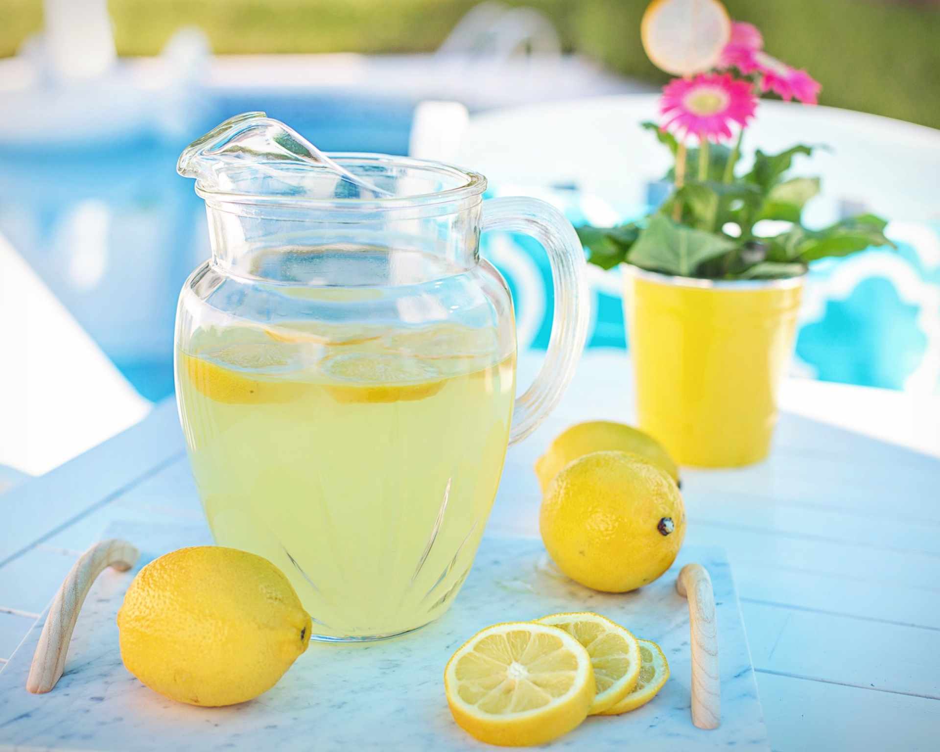 Limonáda z citrónov v džbáne, citróny celé aj nakrájané v pozadí