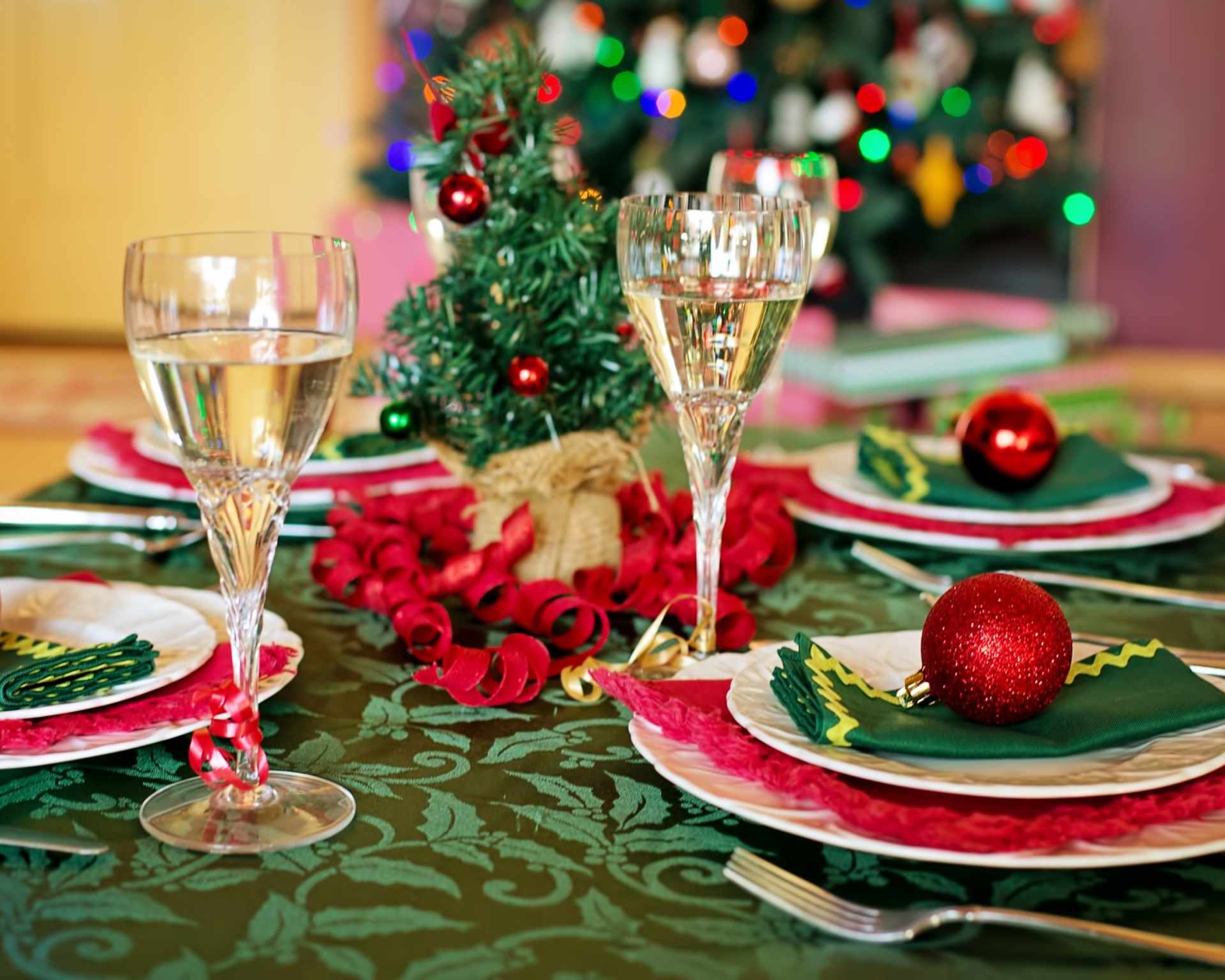 Stôl prestretý na večeru na Štedrý deň s pohármi šampanského a vianočným stromčekom