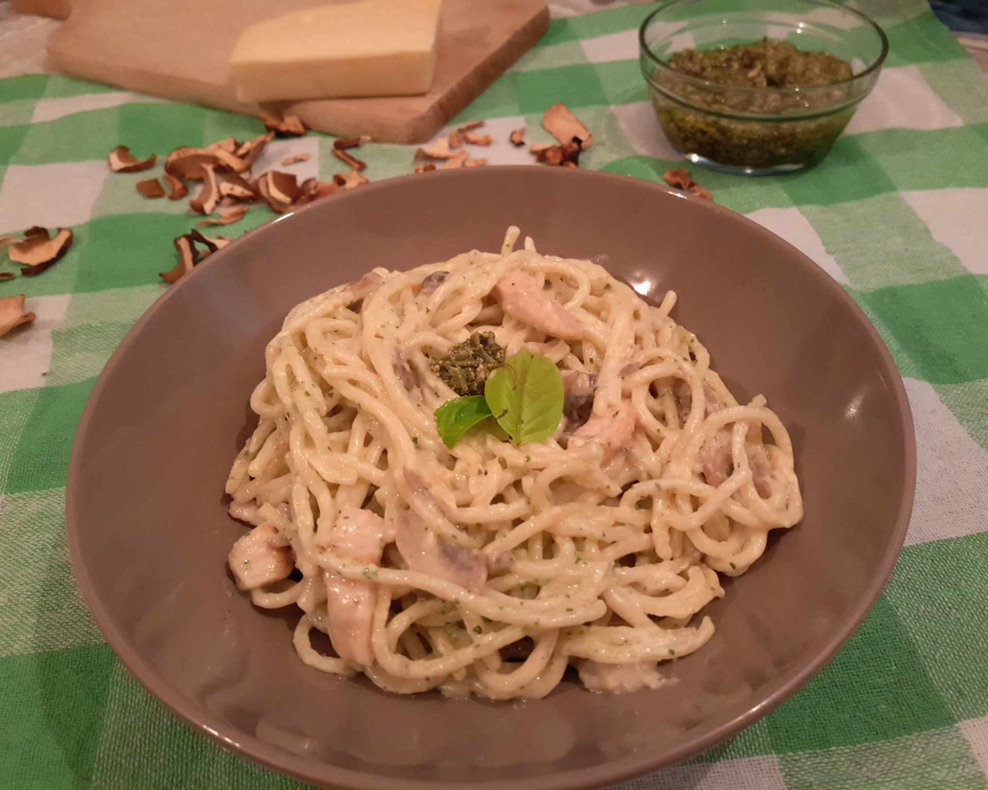 Špagety s bazalkovým pestom s hubami ozdobené čerstvou bazalkou.
