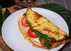Omeleta plnená syrom, šunkou, paradajkami a špenátom zložená na polku