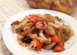 Treska upečená v rúre s pečenými korenenými zemiakmi, paradajkami a čiernymi olivami naložená na bielom tanieri