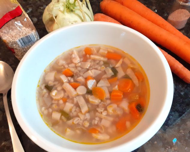 Plná miska polievky s mrkvou, krúpkami, petržlenom, kalerábom, zelerom a cibuľkou