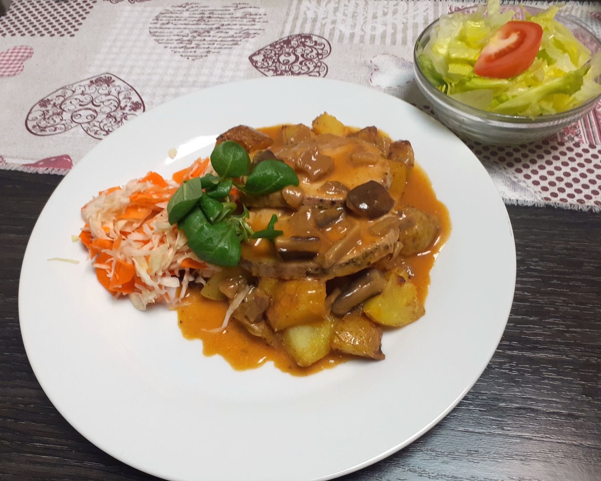 Hubové bravčové mäsko s omáčkou, varené zemiaky v šupke s mrkvovo-kapustovým šalátikom, v pozadí hlávkový šalát s paradajkou