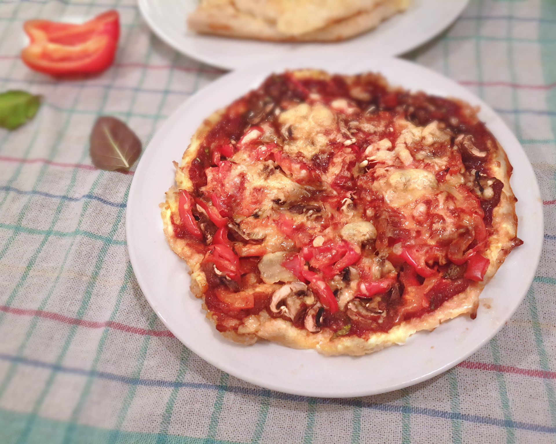 Krásny tenký slaný okrúhly pizza koláč s červenou paprikou, šampiňónmi a syrom na bielom okrúhlom tanieri