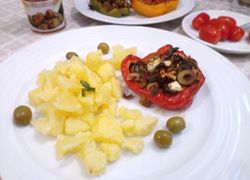 Červená paprika s olivovo-syrovou plnkou a varenými zemiakmi, dookola rozsypané olivy