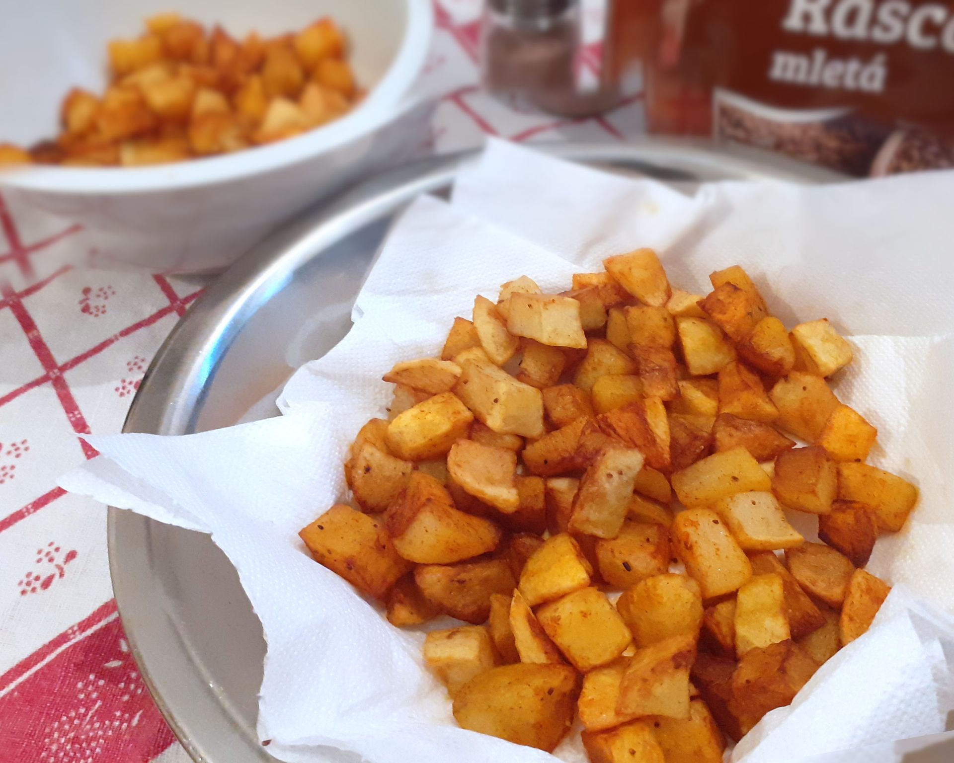 Na kocky nakrájané zemiaky upečené pekne do chrumkava posypané rascou a paprikou na bielej servítke.
