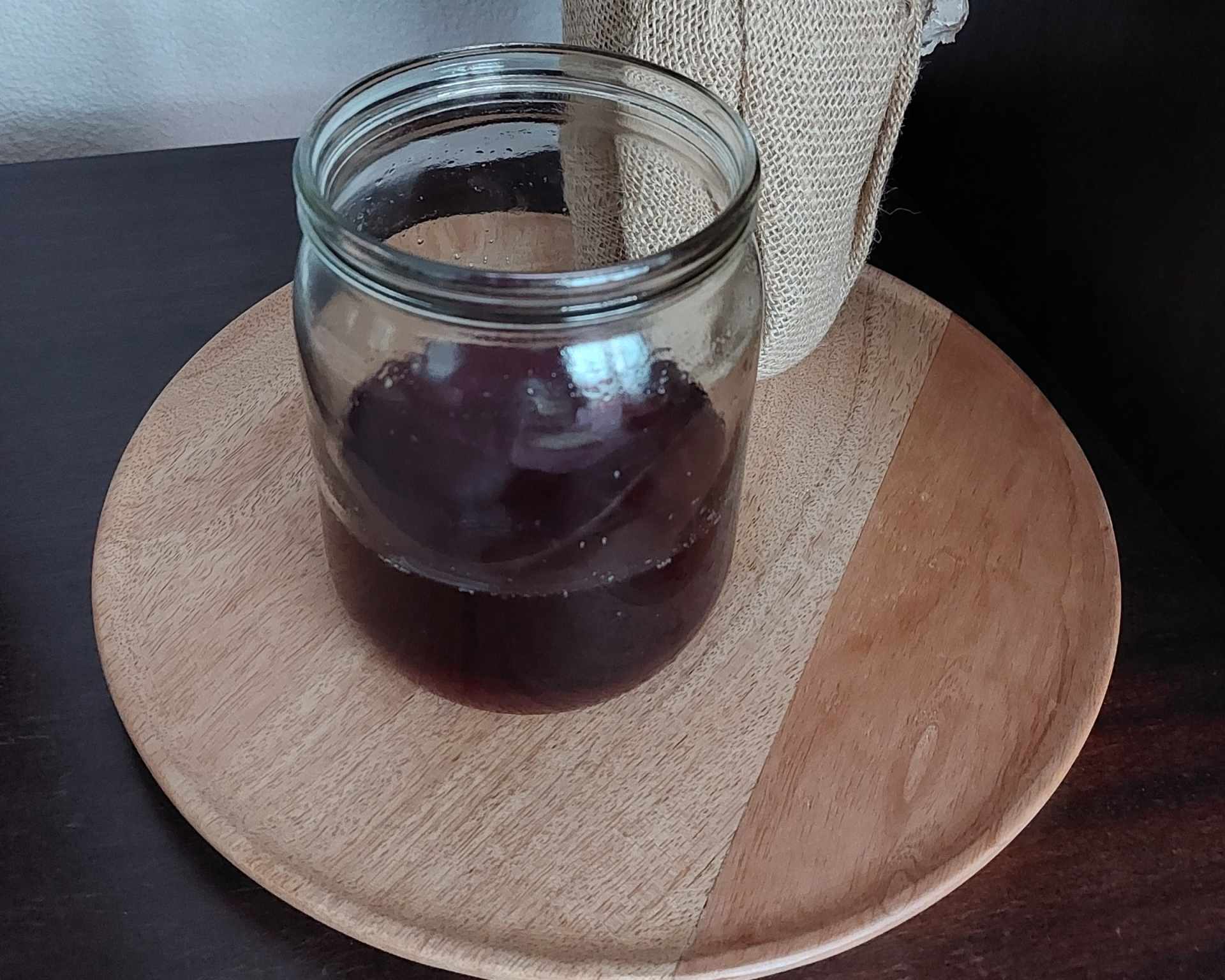 Limonáda z čerešní v sklenenom pohári na drevenej okrúhlej podložke