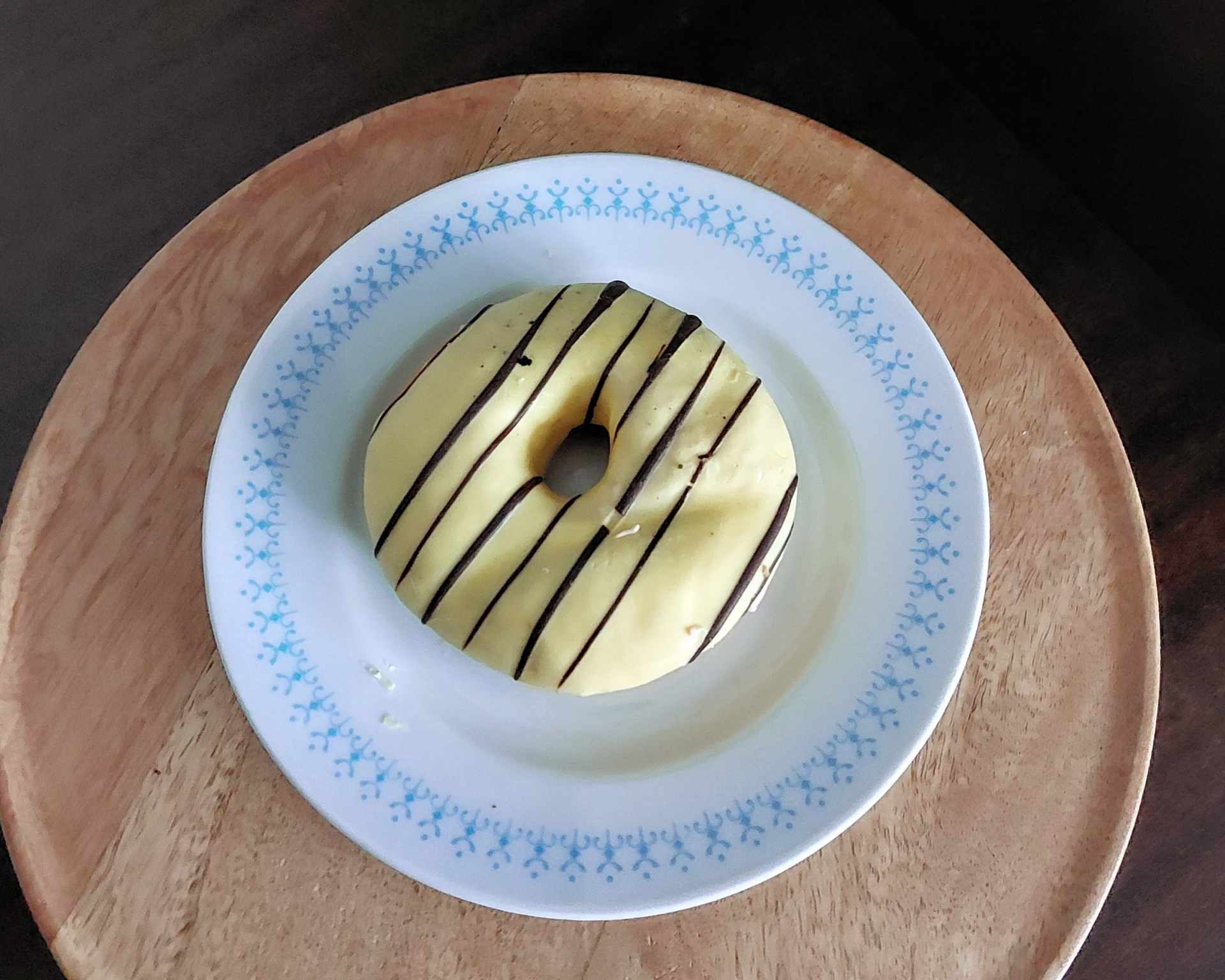 Šiška bez lepku s bielou polevou a čokoládou na bielom tanieri s modrým vzorovaným okrajom