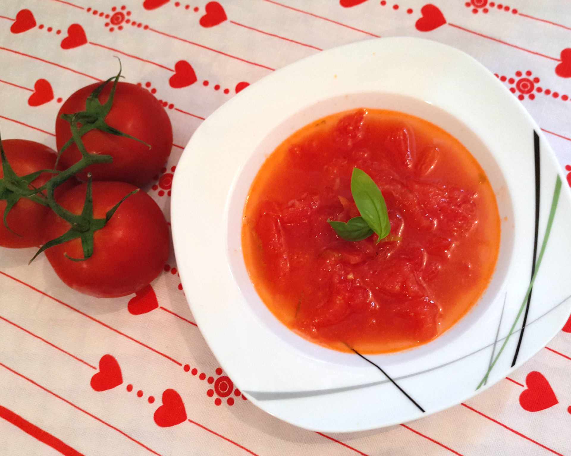Čerstvé olúpané nakrájané paradajky v červenej polievke ozdobenej bazalkou