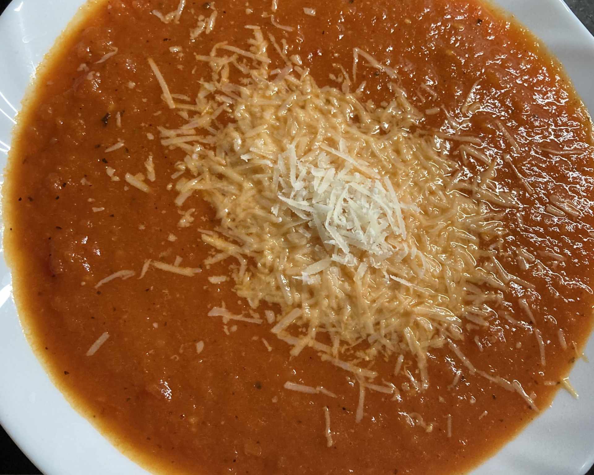 Paradajková polievka, pečené paradajky, posypané množstvom strúhaného syra
