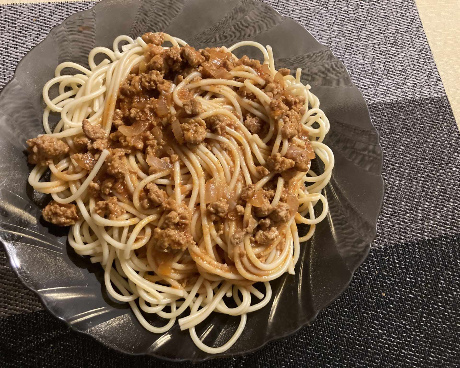 Hotové špagety s mletým mäsom na čiernom priesvitnom tanieri