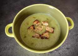 Hotový vegánsky brokolicový krém s chlebovými krutónmi v zelenej miske s uškami