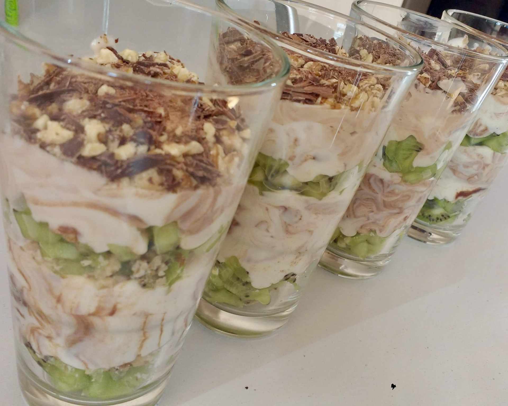 Hotový nugátový dezert, kiwi, čokoláda a orechy v sklenených pohároch