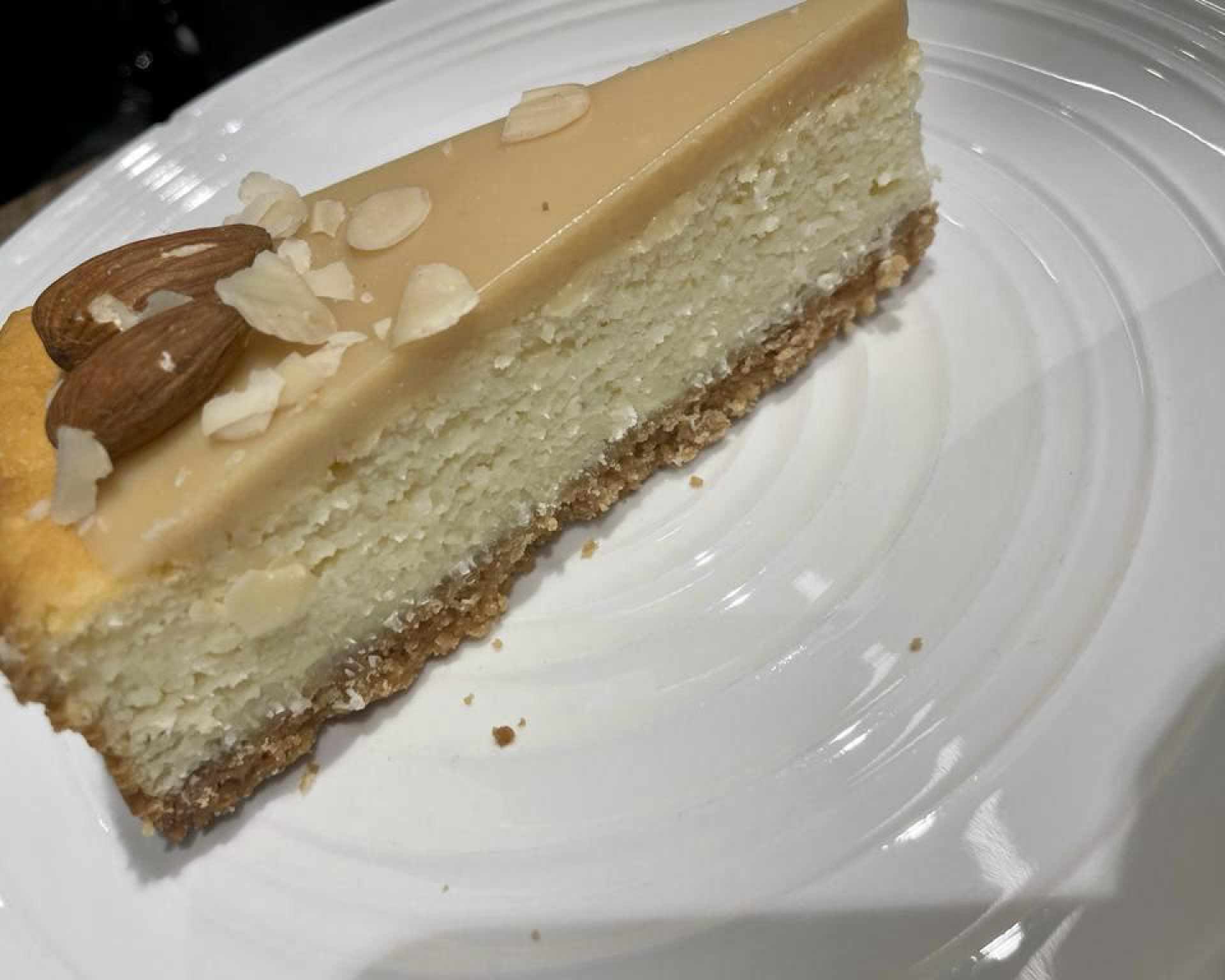 Hotový mandľový cheesecake ozdobený celými mandľami a mandľovými lupienkami