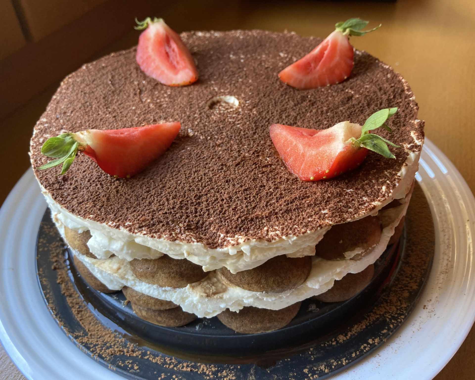 Hotové tiramisu ako torta posypané kakaom a dozdobené jahodami