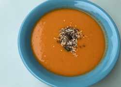 Hotová krémová polievka z červenej šošovice a paradajok posypaná rôznymi semienkami