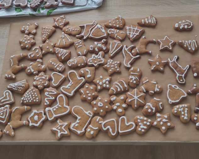 Perníčky rôznych tvarov s bielou polevou na papieri na pečenie