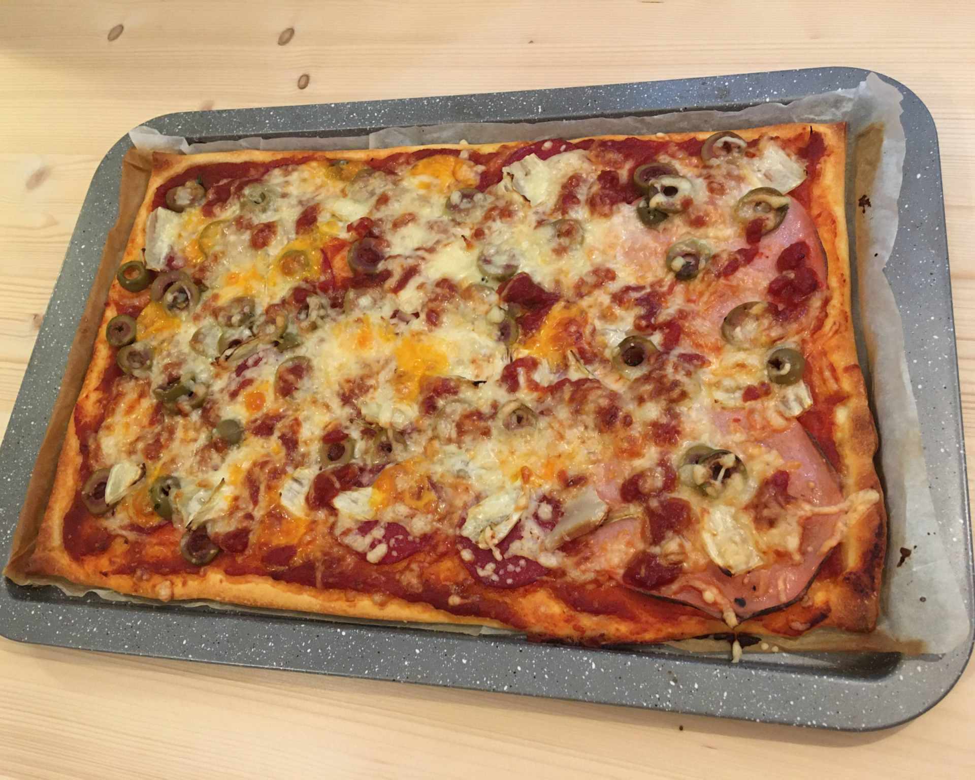 Paradajková pizza s jemnou a suchou salámou, zelené olivy, rozšľahané vajce, syr