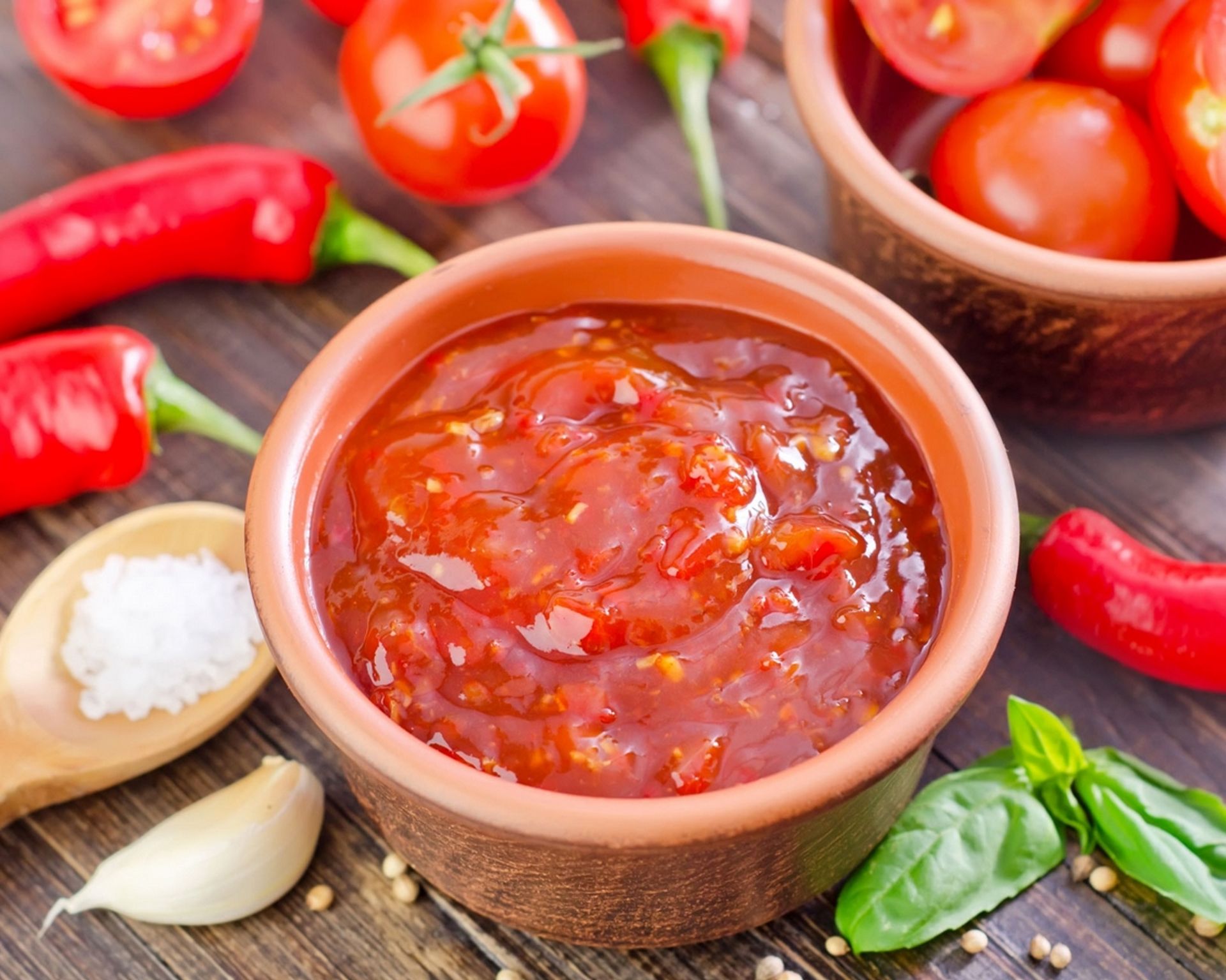 Červená salsa omáčka v miske, okolo štipľavé papričky