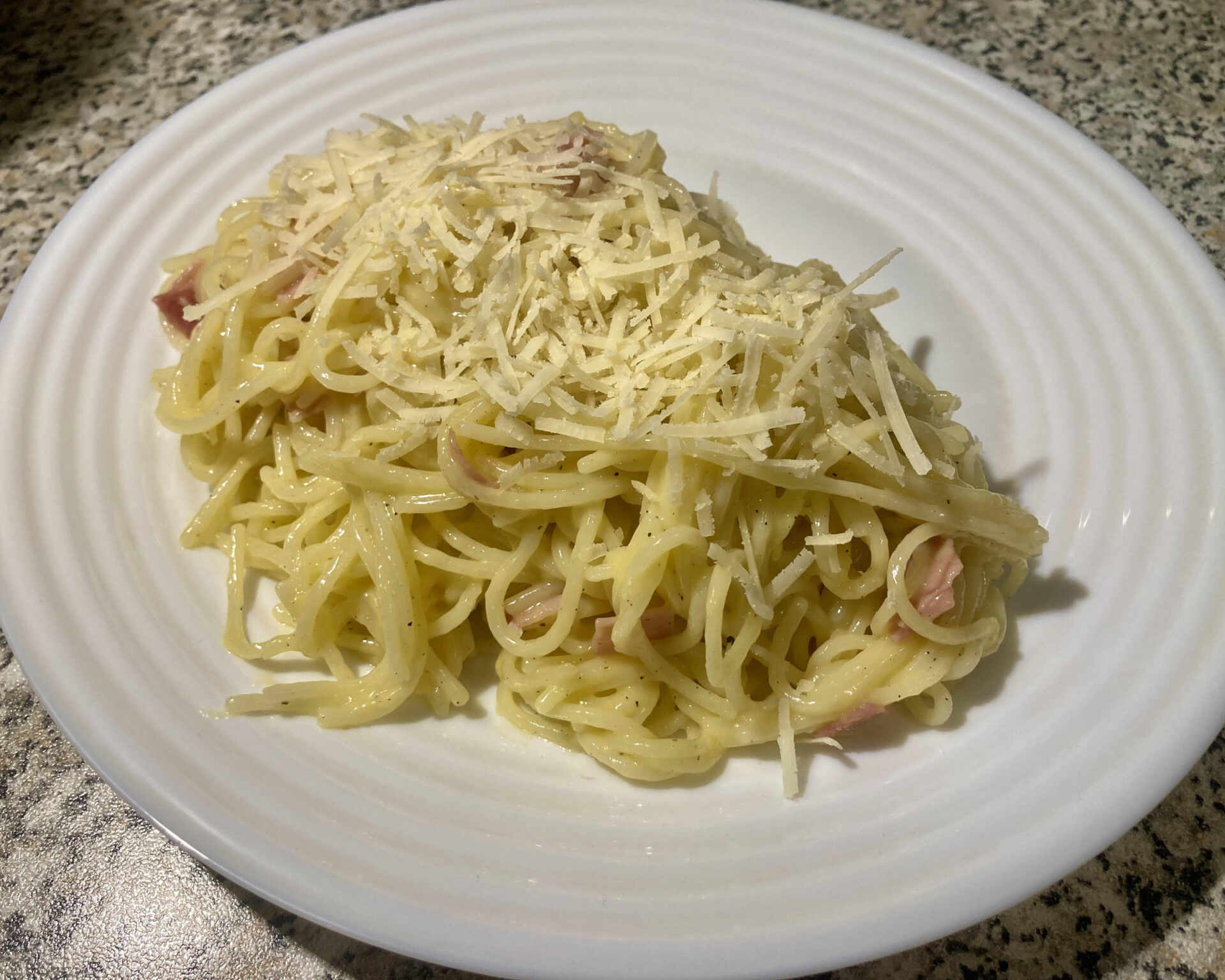 Hotové špagety carbonara posypané syrom Pecorino