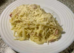 Hotové špagety carbonara posypané syrom Pecorino