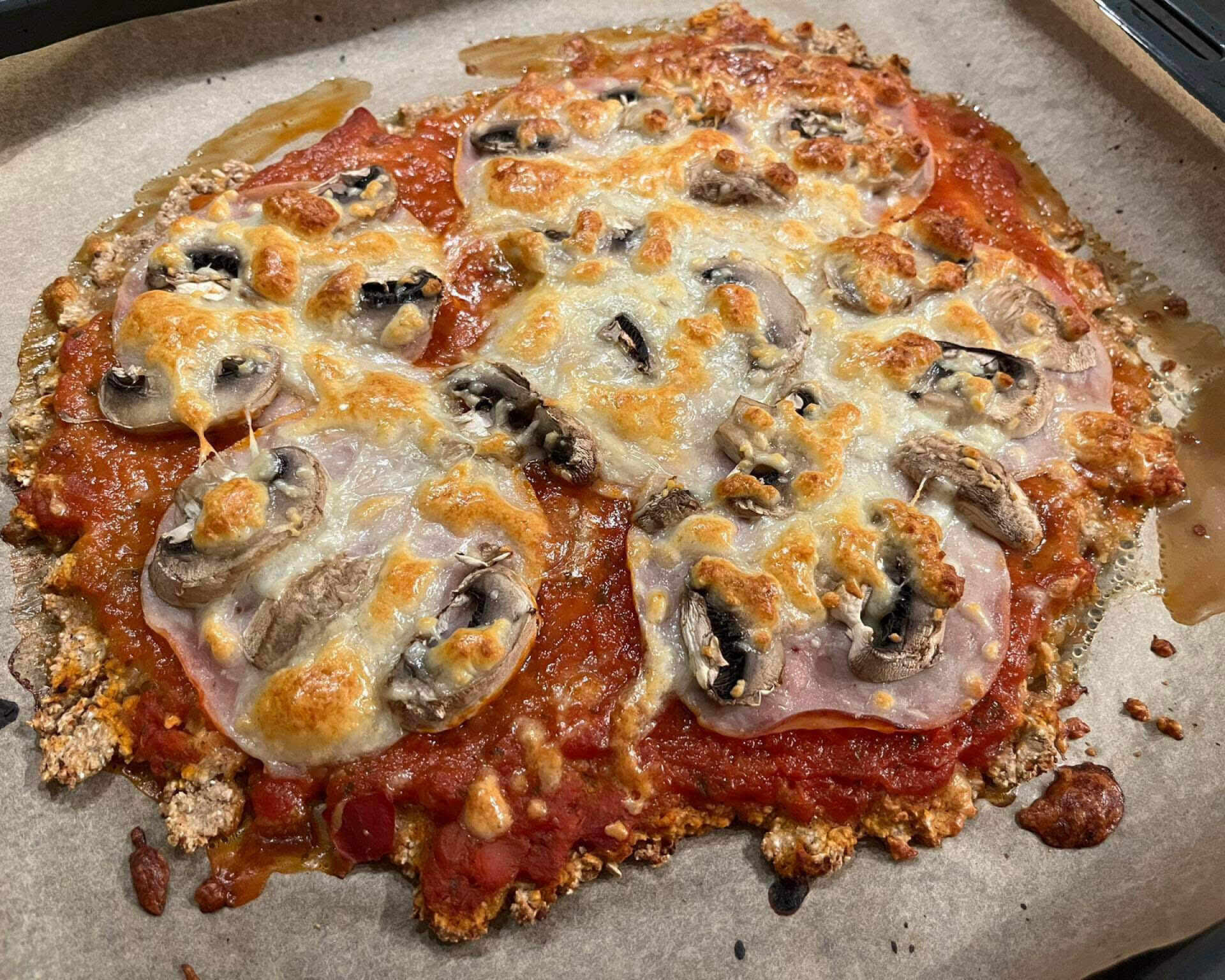 Hotová pizza z ovsených vločiek, paradajkový základ, šunka, šampiňóny, syr.