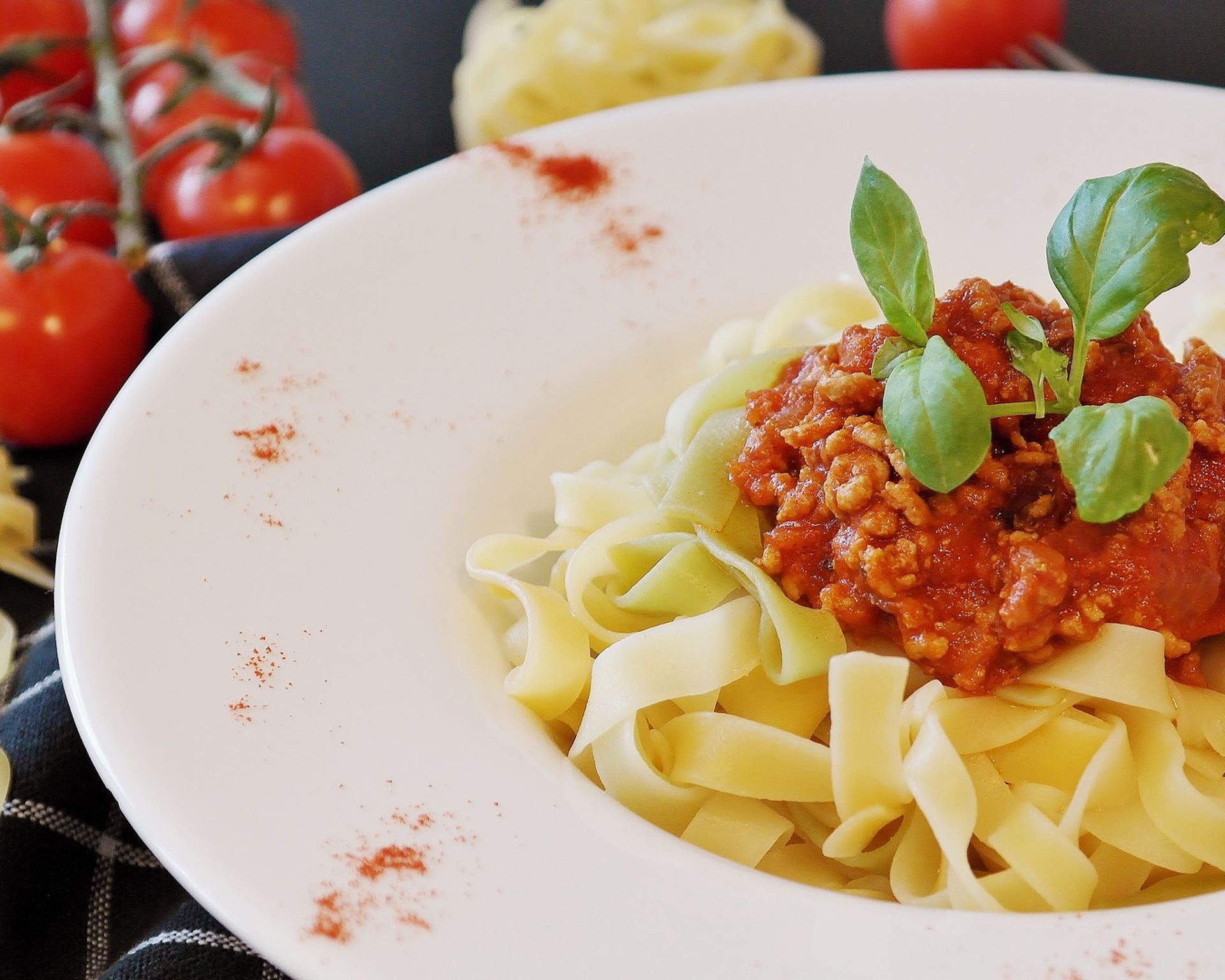 Tagliatelle s mletým mäsom na tanieri, ozdobené bazalkou