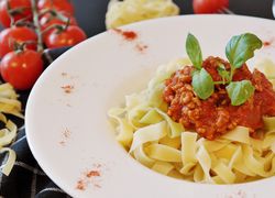 Tagliatelle s mletým mäsom na tanieri, ozdobené bazalkou