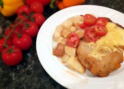 Rezeň so syrom, haruľové cestíčko, paradajky a varené zemiaky na tanieri