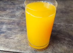 Pomarančový džús v pohári na drevenom stole