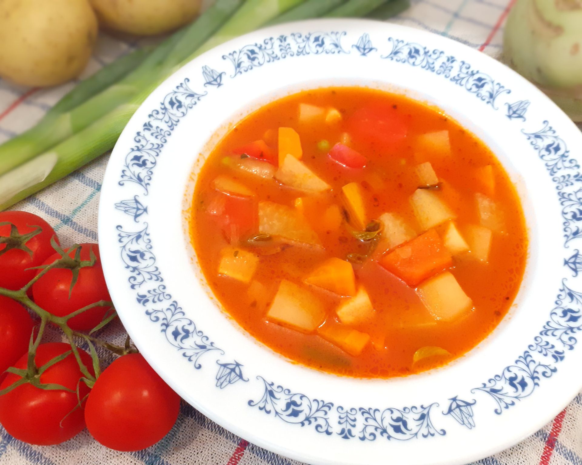Červená polievka v modro-bielom tanieri so zemiakmi a zeleninou