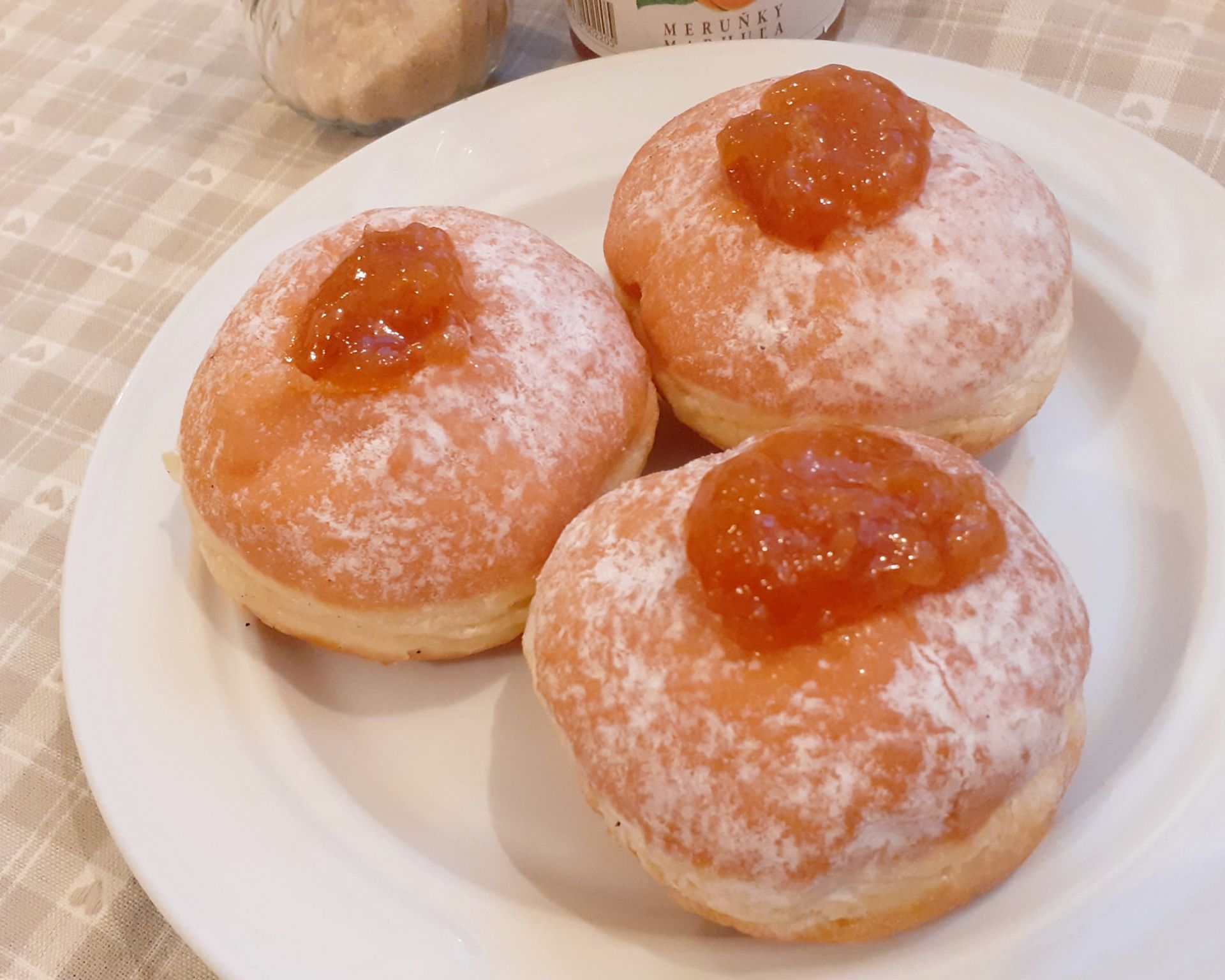 Domáce šišky na tanieri s marhuľovým džemom posypané cukrom