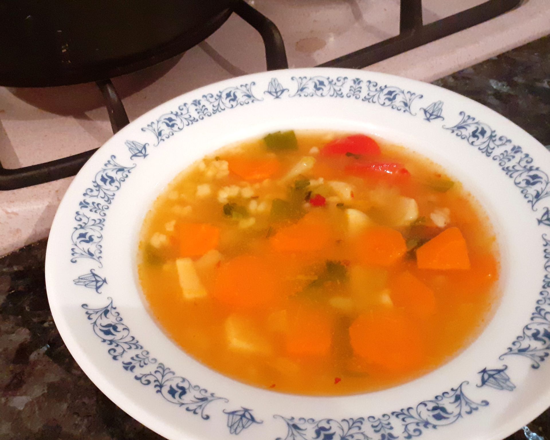 Biela miska s modrým ozdobným okrajom so zeleninovou polievkou, ostrá polievka
