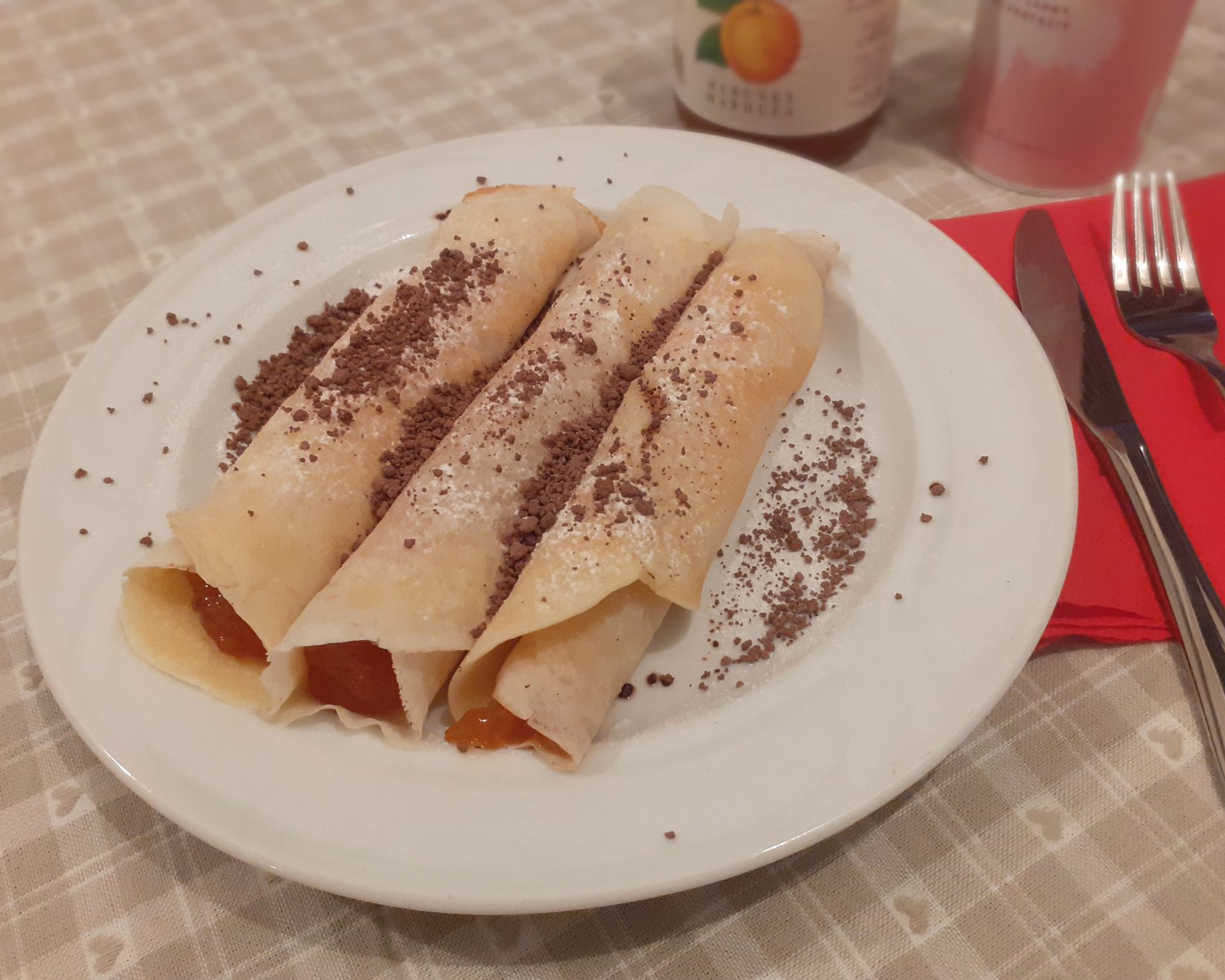 Tri zakrútené palacinky plnené džemom, posypané cukrom a grankom