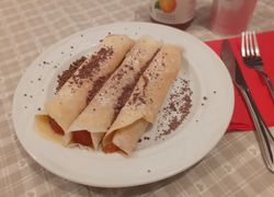 Tri zakrútené palacinky plnené džemom, posypané cukrom a grankom