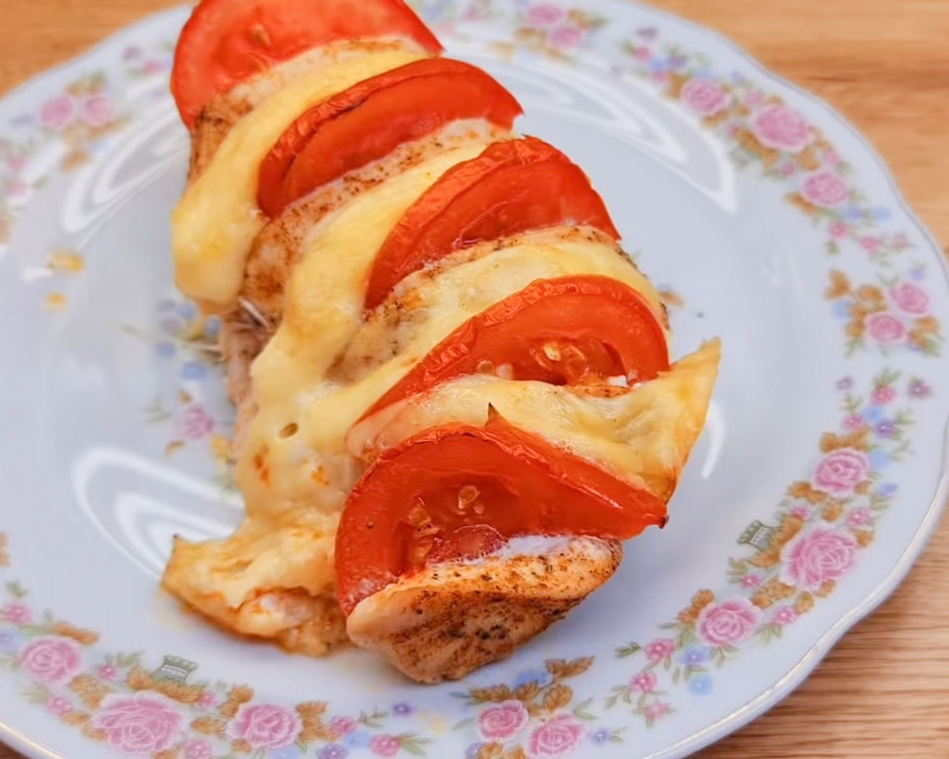 Kuracie mäsko s paradajkami a tvrdý syr na kvietkovanom tanieri