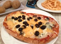 Pečená bruschetta syrová s olivami. Tvarom aj cestom pripomína pizzu.
