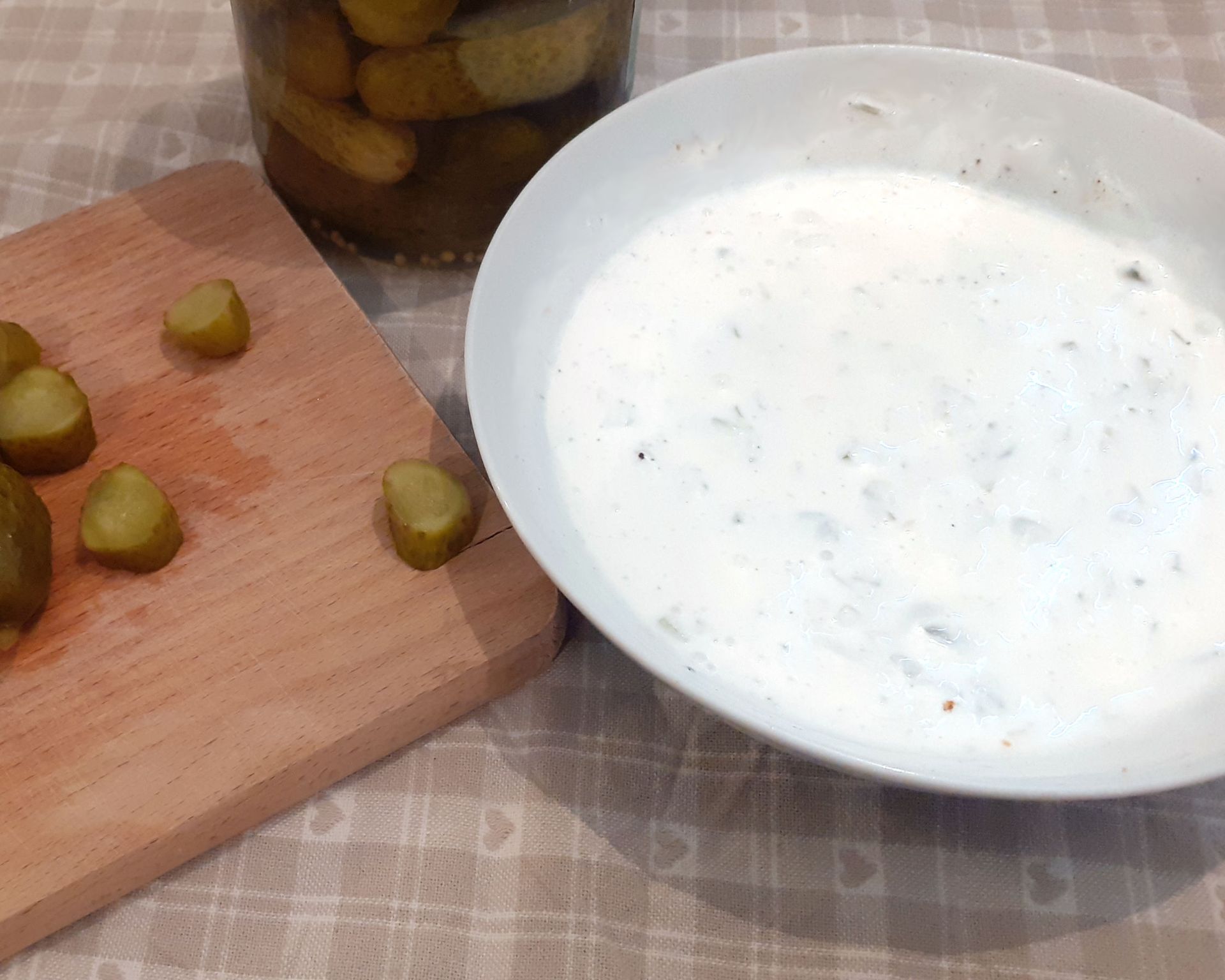 Hotová tatarka z jogurtu v miske a pri nej nakrájané uhorky