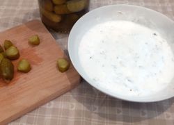 Hotová tatarka z jogurtu v miske a pri nej nakrájané uhorky