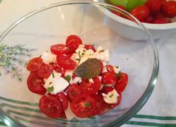 Šalát z paradajok a mozzarelly v sklenenej miske s ozdobným lístkom bazalky