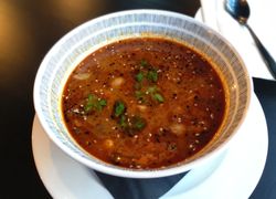 Hotová polievka Tom Yum vo veľkej miske ozdobená koriandrom a sezamom