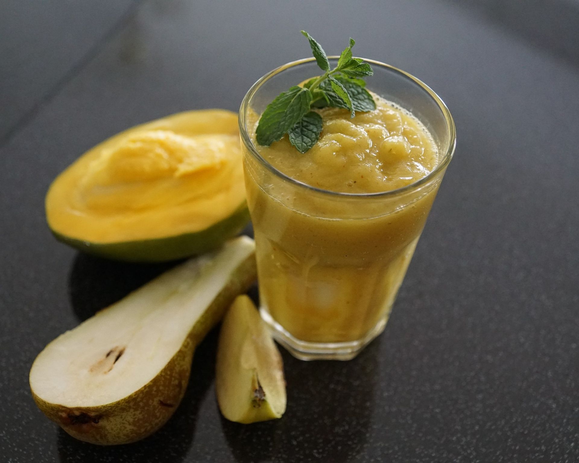 Nápoj v priesvitnom pohári, prekrojené mango a hruška