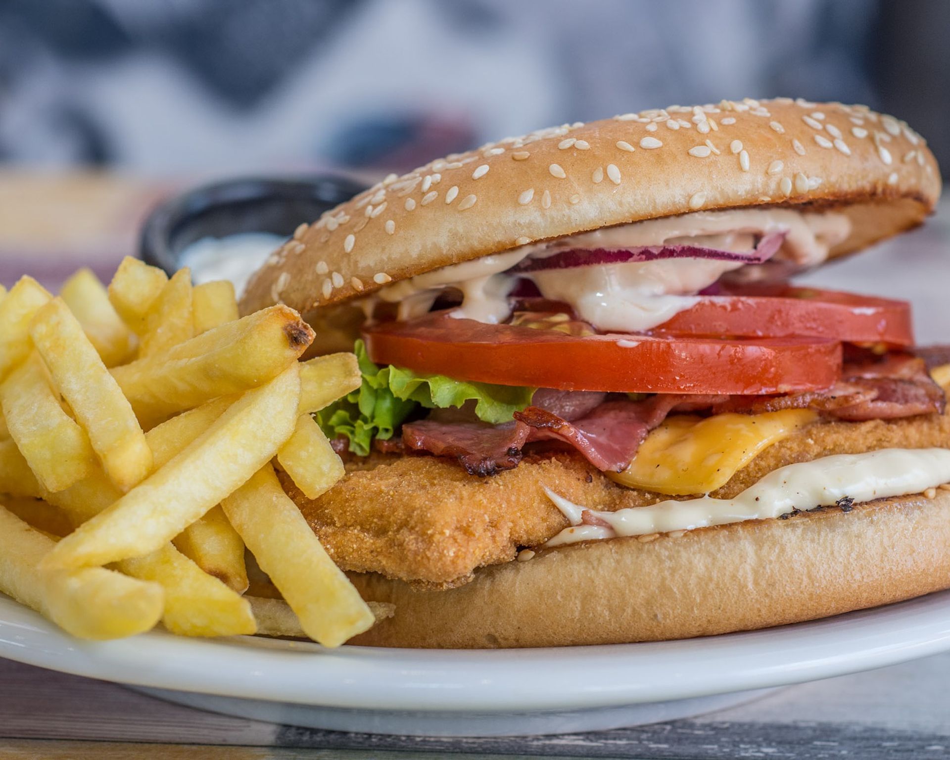 Čerstvo pripravený hamburger plnený vypraženým syrom, zeleninou a omáčkou. Nechýbajú ani hranolky.