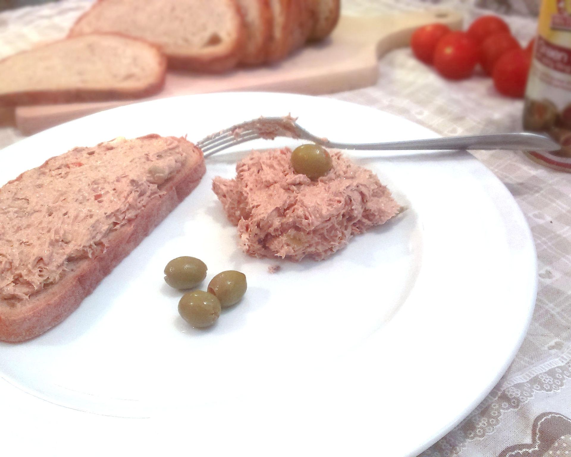 Pomazánka natretá na chlebík, vedľa nátierka s olivou a zelené olivy