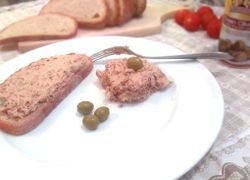 Pomazánka natretá na chlebík, vedľa nátierka s olivou a zelené olivy